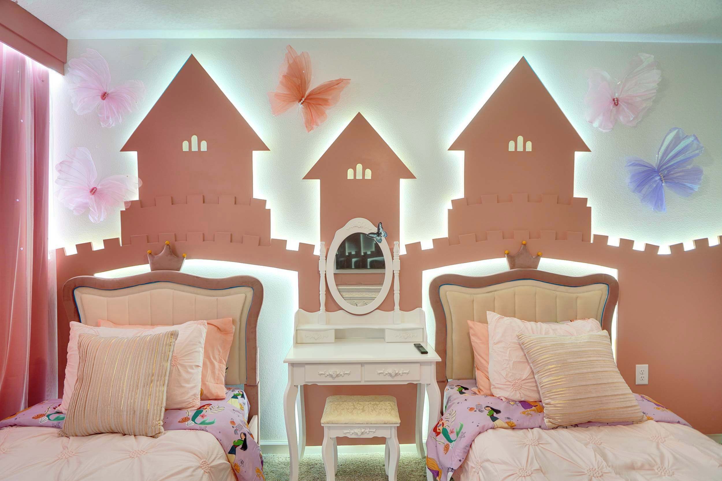 A bedroom with two beds, a vanity table, and a mirror.