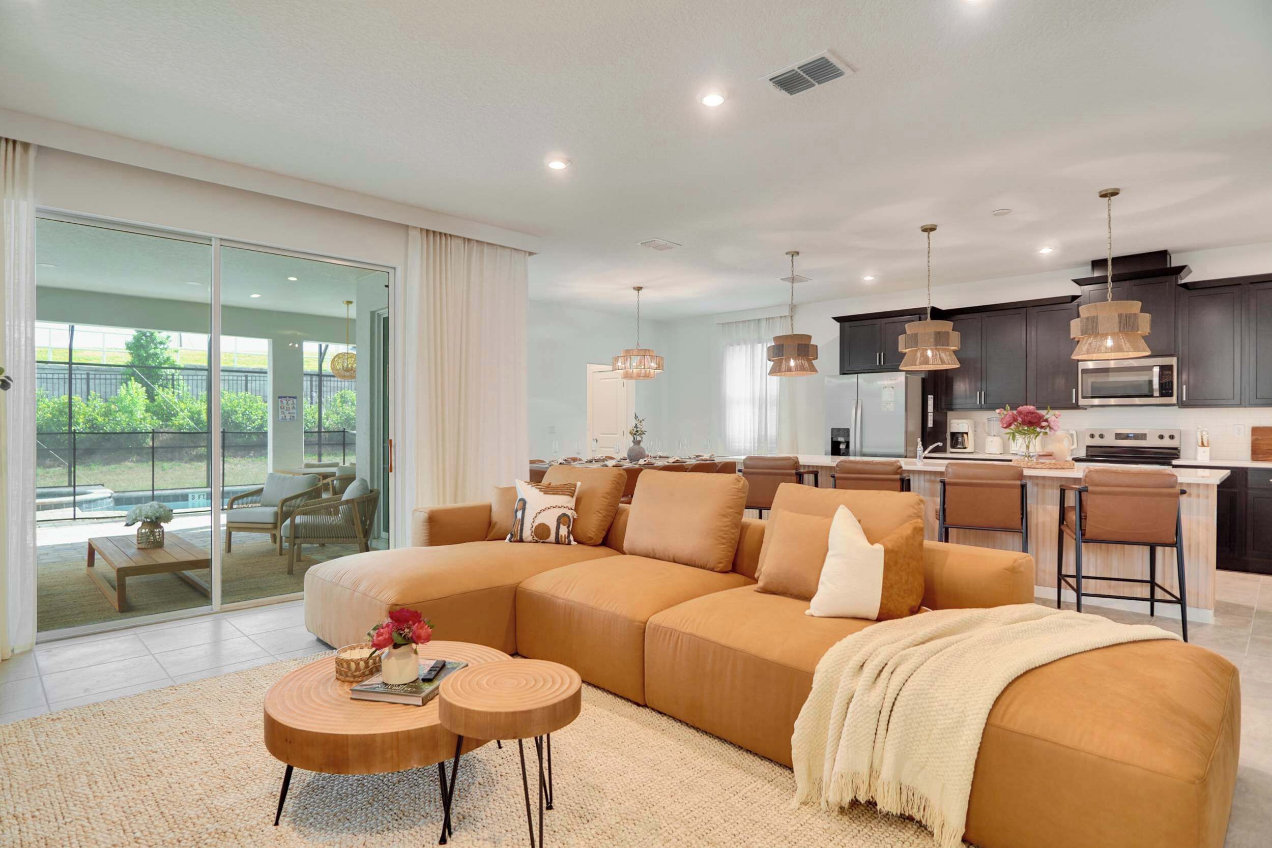 A modern living room with a large sectional sofa, a coffee table, and a dining area with bar stools.
