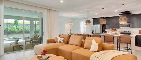 A modern living room with a large sectional sofa, a coffee table, and a dining area with bar stools.