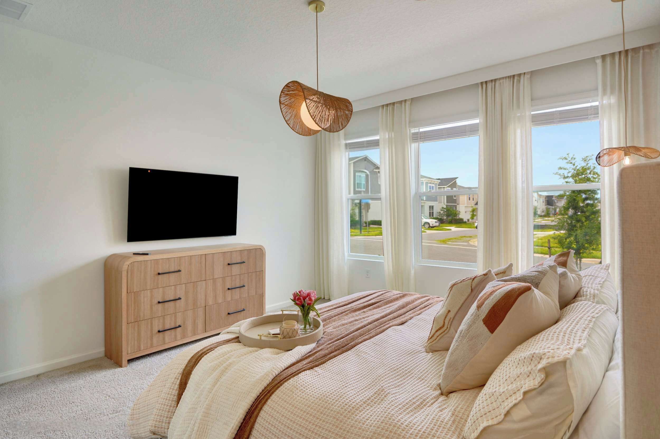 A modern bedroom with a large bed, a TV on the wall, and a view of the outside.