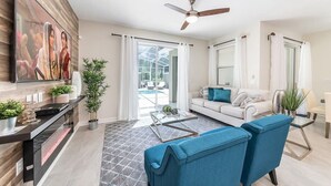 A modern living room with a sofa, coffee table, and TV. - Chic, Spacious With Private Pool, Ideal Location (Kissimmee)