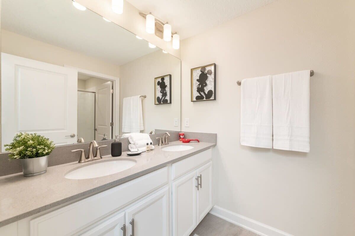 A bathroom with two sinks, a large mirror, and a towel rack.