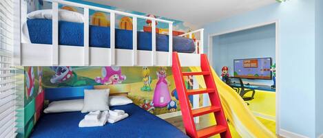 A child's bedroom with bunk beds, a slide, and a Mario-themed wall.