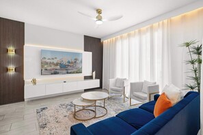 A modern living room with a sofa, chairs, a coffee table, a ceiling fan, and a large painting on the wall. - Magical Retreat Near Disney, Private Pool (Davenport)