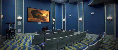 A conference room with rows of chairs, a large painting on the wall, and a patterned carpet.