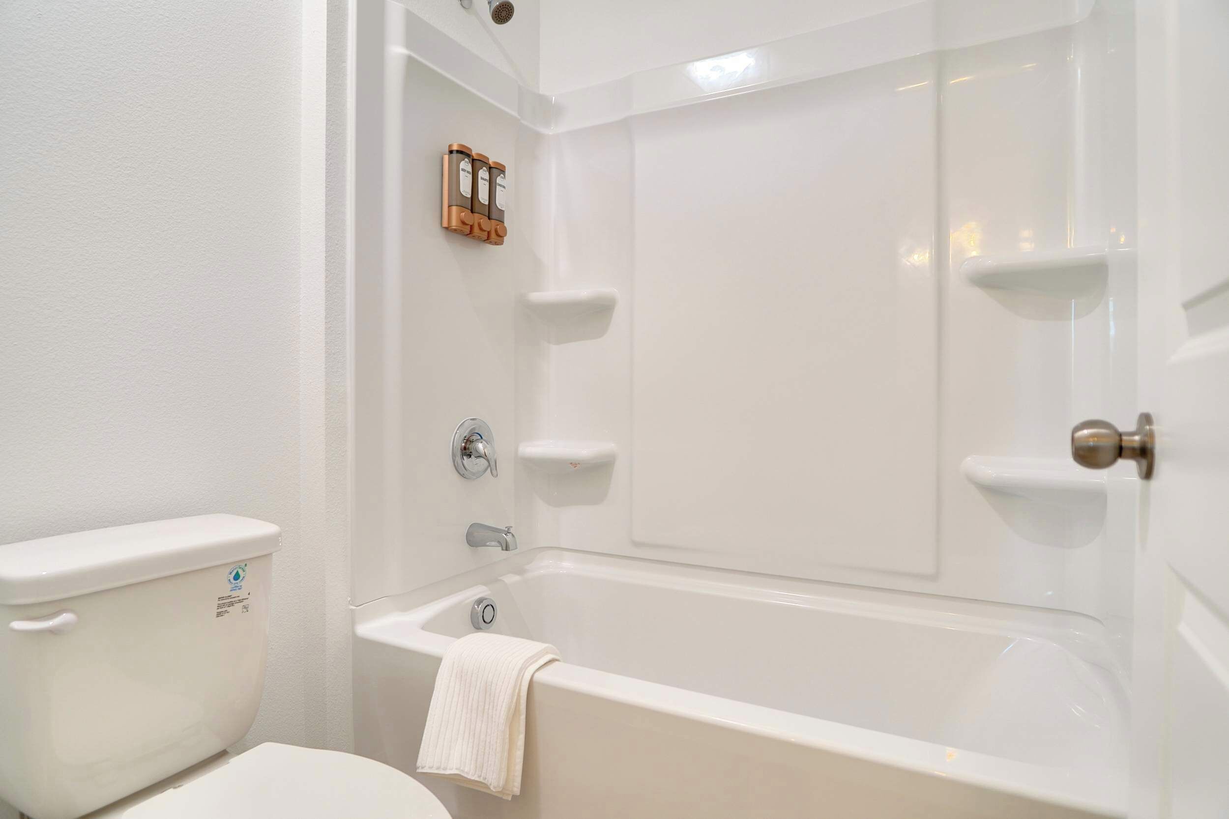 Une salle de bain avec des toilettes blanches, une baignoire et un espace douche.