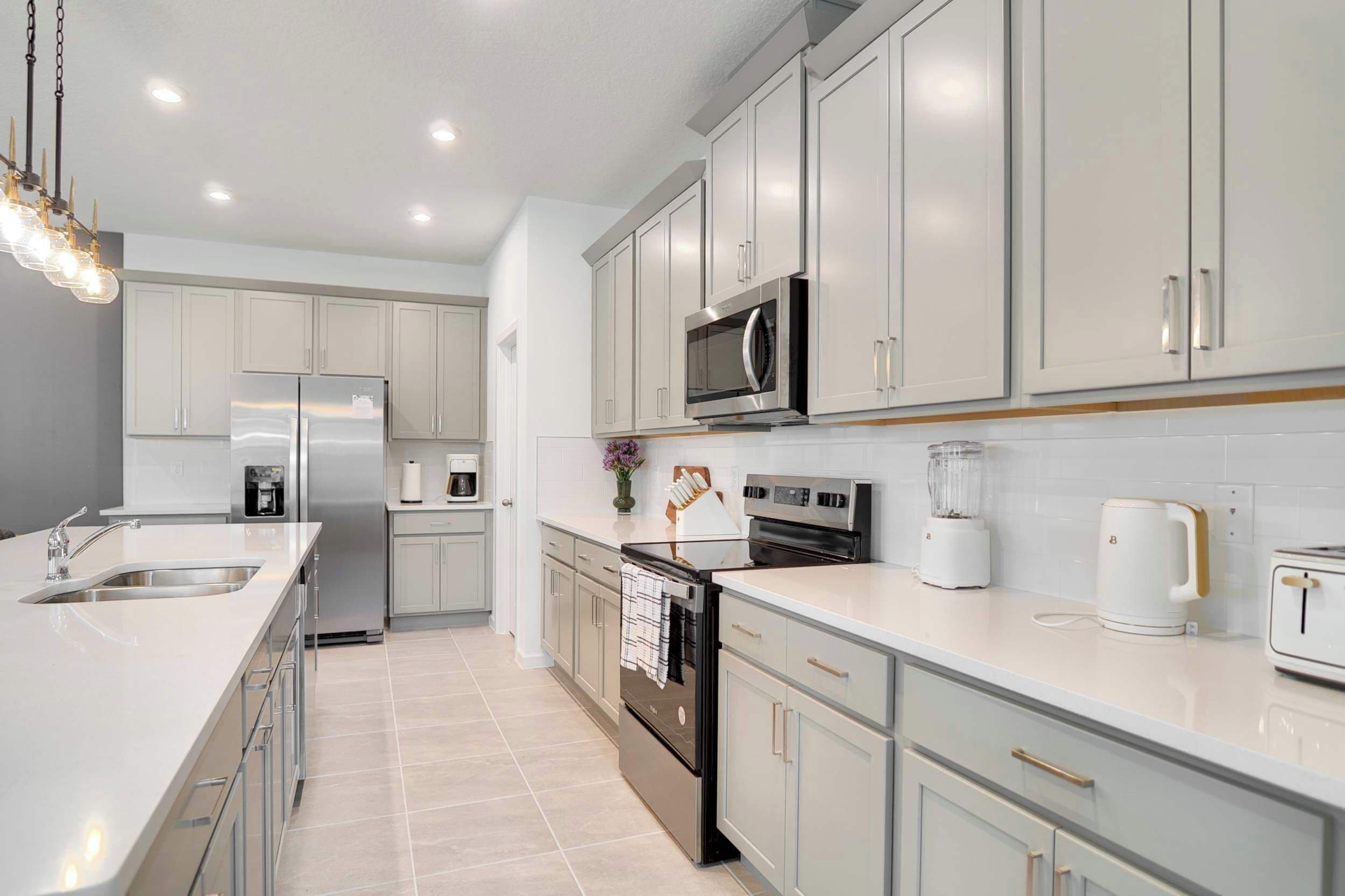 A modern kitchen with stainless steel appliances, white cabinetry, and a central island.