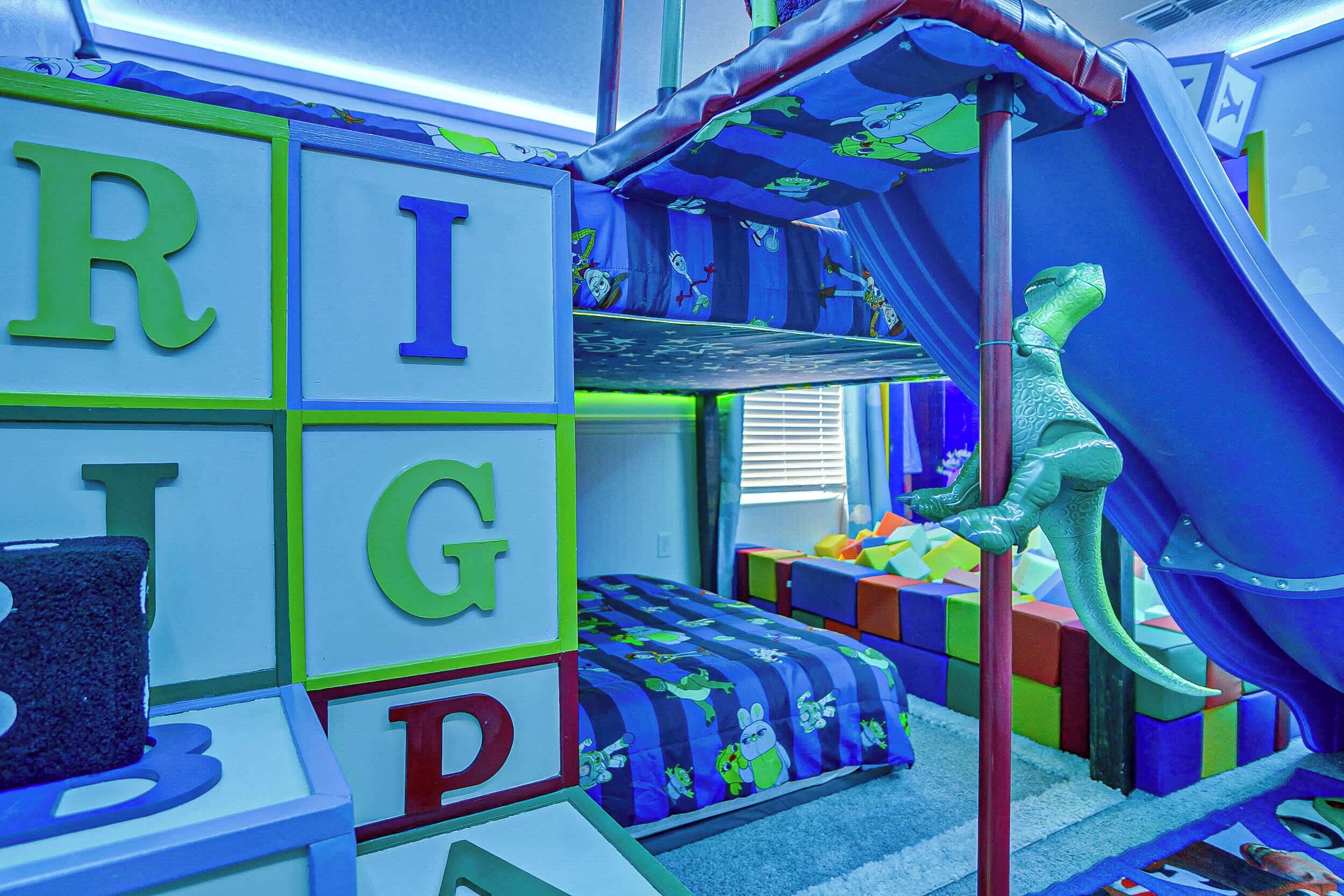 Un espace de jeux pour enfants avec des blocs de couleurs vives, un toboggan et une décoration sur le thème des dinosaures.