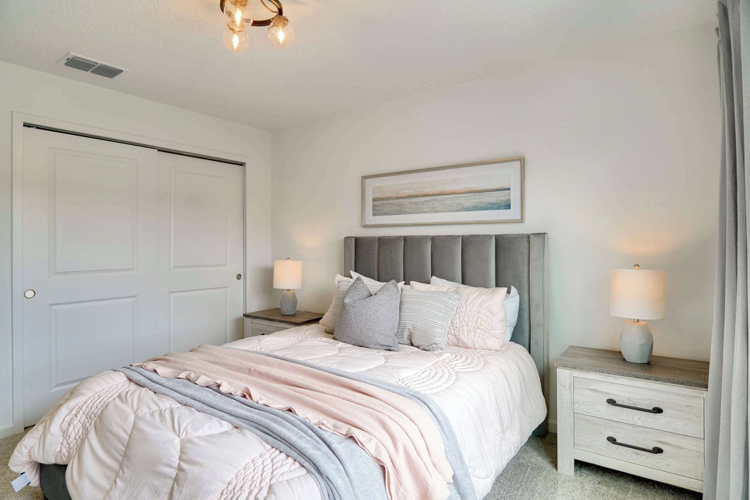 A bedroom with a bed, nightstands, a headboard, a painting, and a door.