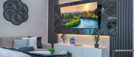 A modern living room with a mounted TV, a white console table, and a grey sofa.