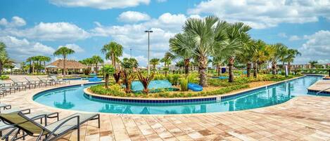 A swimming pool with palm trees, lounge chairs, and a tiled deck.