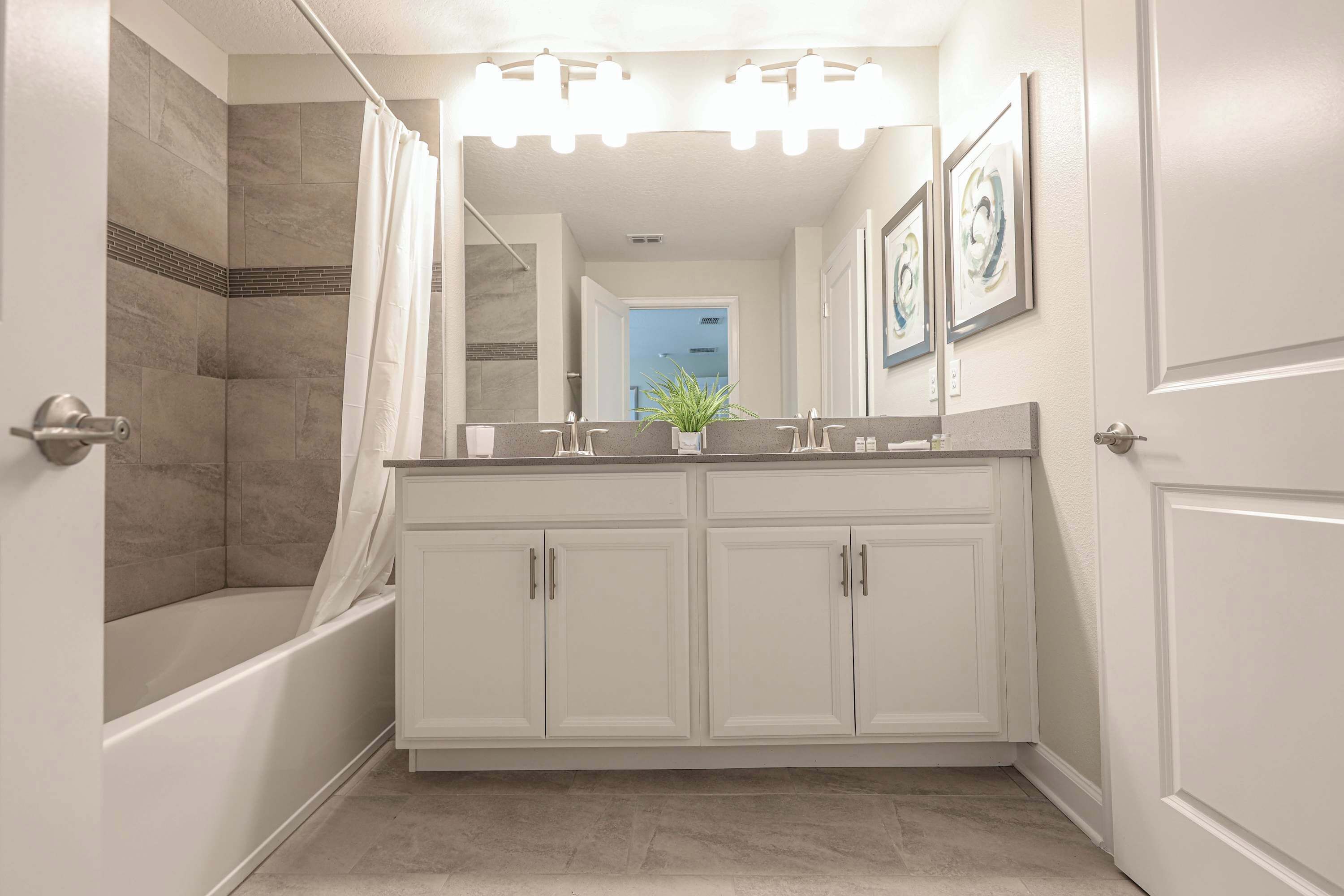 A modern bathroom with a bathtub, double vanity, and a shower area.