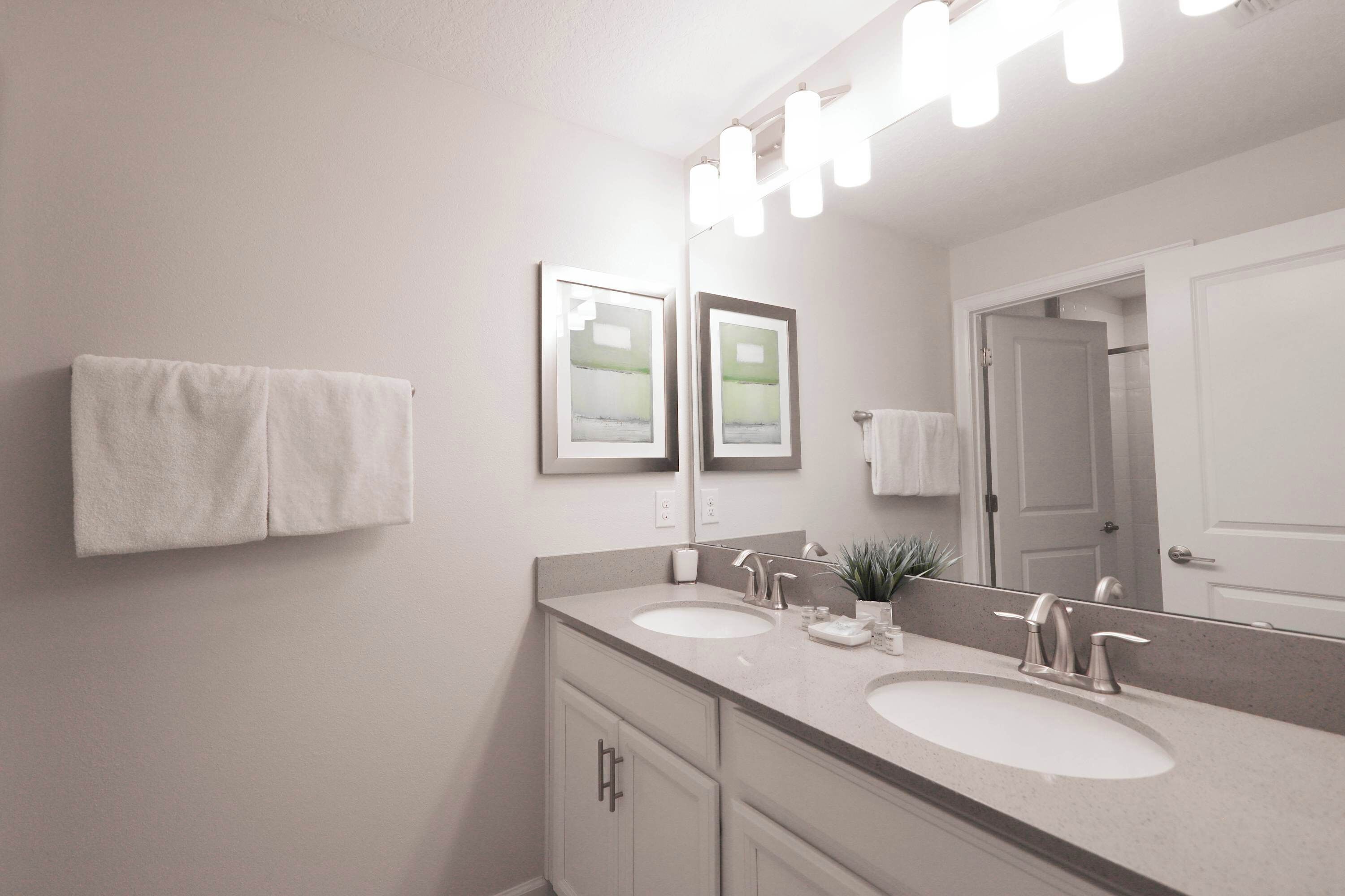 A bathroom with two sinks, a large mirror, and a towel rack.