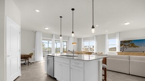 A modern kitchen with a large island, white cabinetry, and pendant lighting. - Elegant 6BR Home Perfect for Families (Clermont)