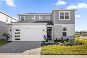 A modern two-story house with a garage, a driveway, and a well-maintained lawn. - Elegant 6BR Home Perfect for Families (Clermont)