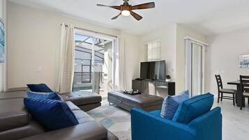 A modern living room with a ceiling fan, a television, and a dining area.
