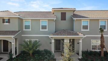 A residential building with a tiled roof, multiple windows, and a central entrance with a small porch.