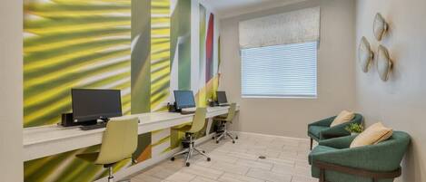 A modern office space with three desks, two chairs, and a green armchair.