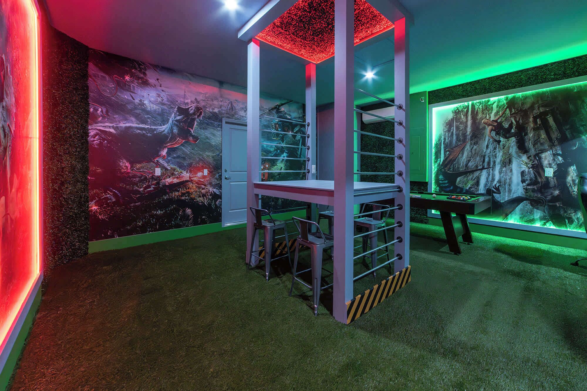 A room with a climbing structure, a pool table, and a mural of a forest scene.