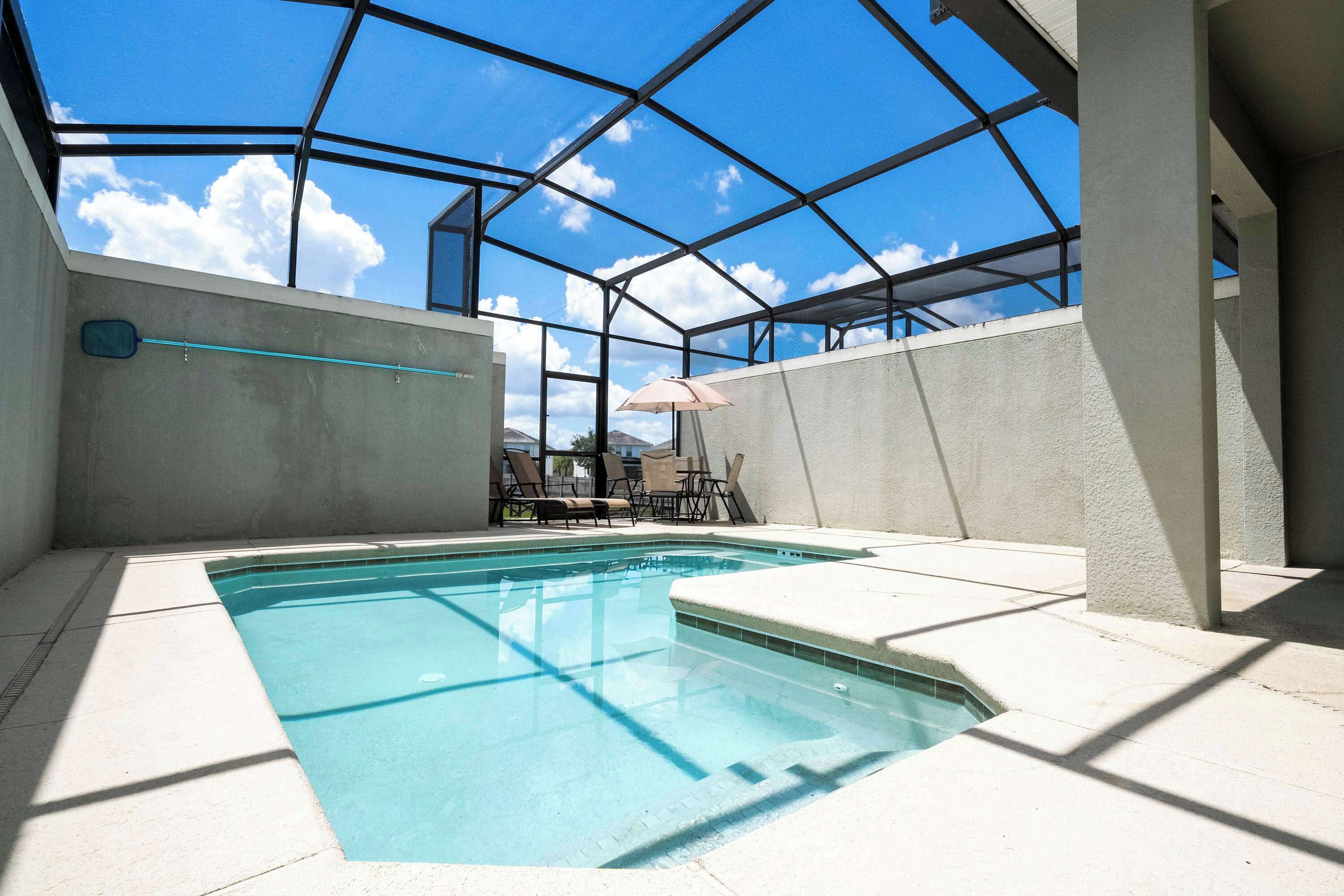 An indoor swimming pool with a glass ceiling, concrete walls, and a clear view of the sky.