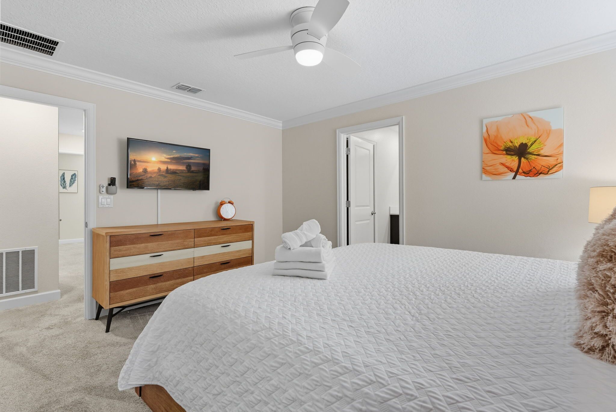 Une chambre à coucher avec un lit, une commode, un tableau et une porte.