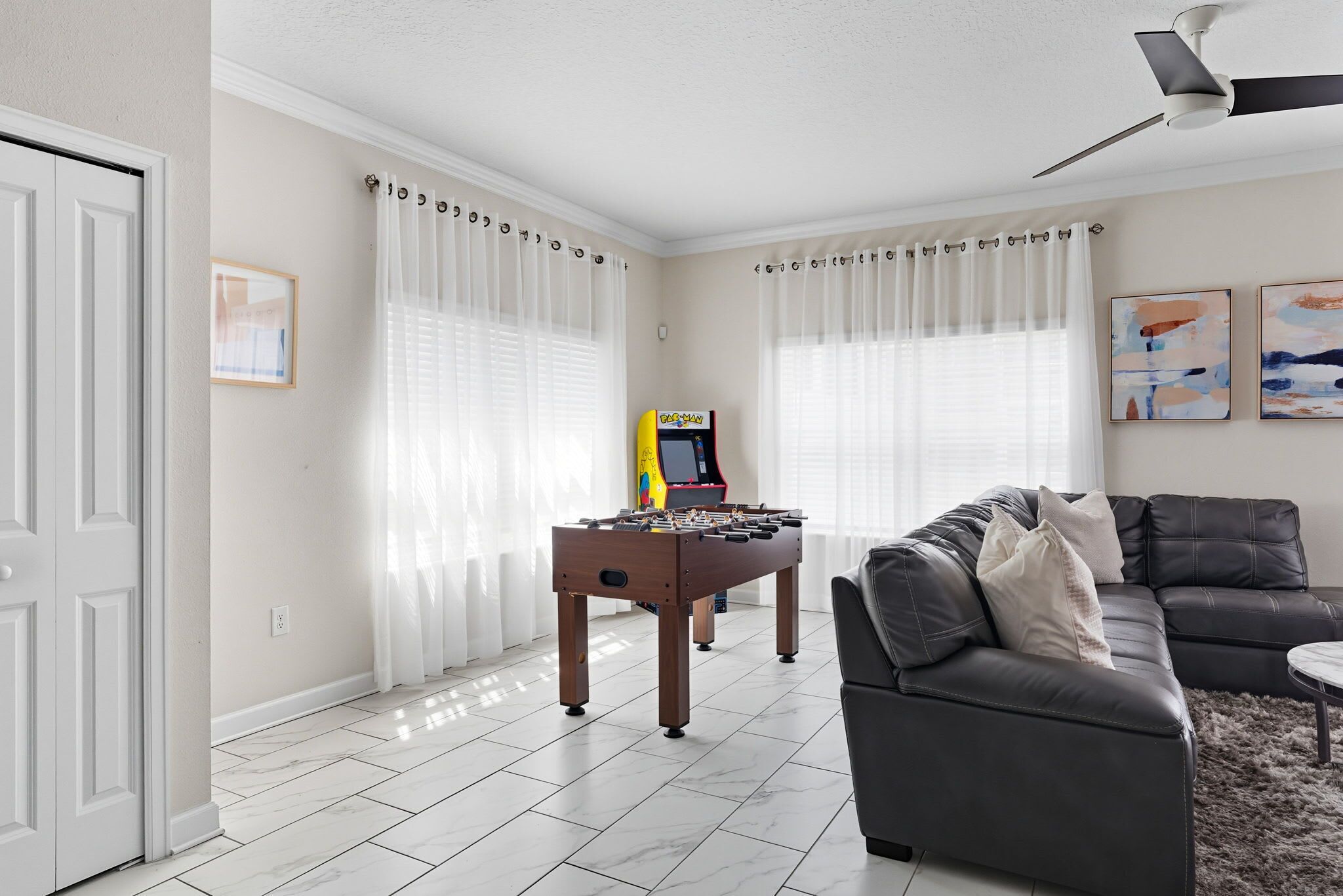 A living room with a foosball table, a sofa, and a ceiling fan.