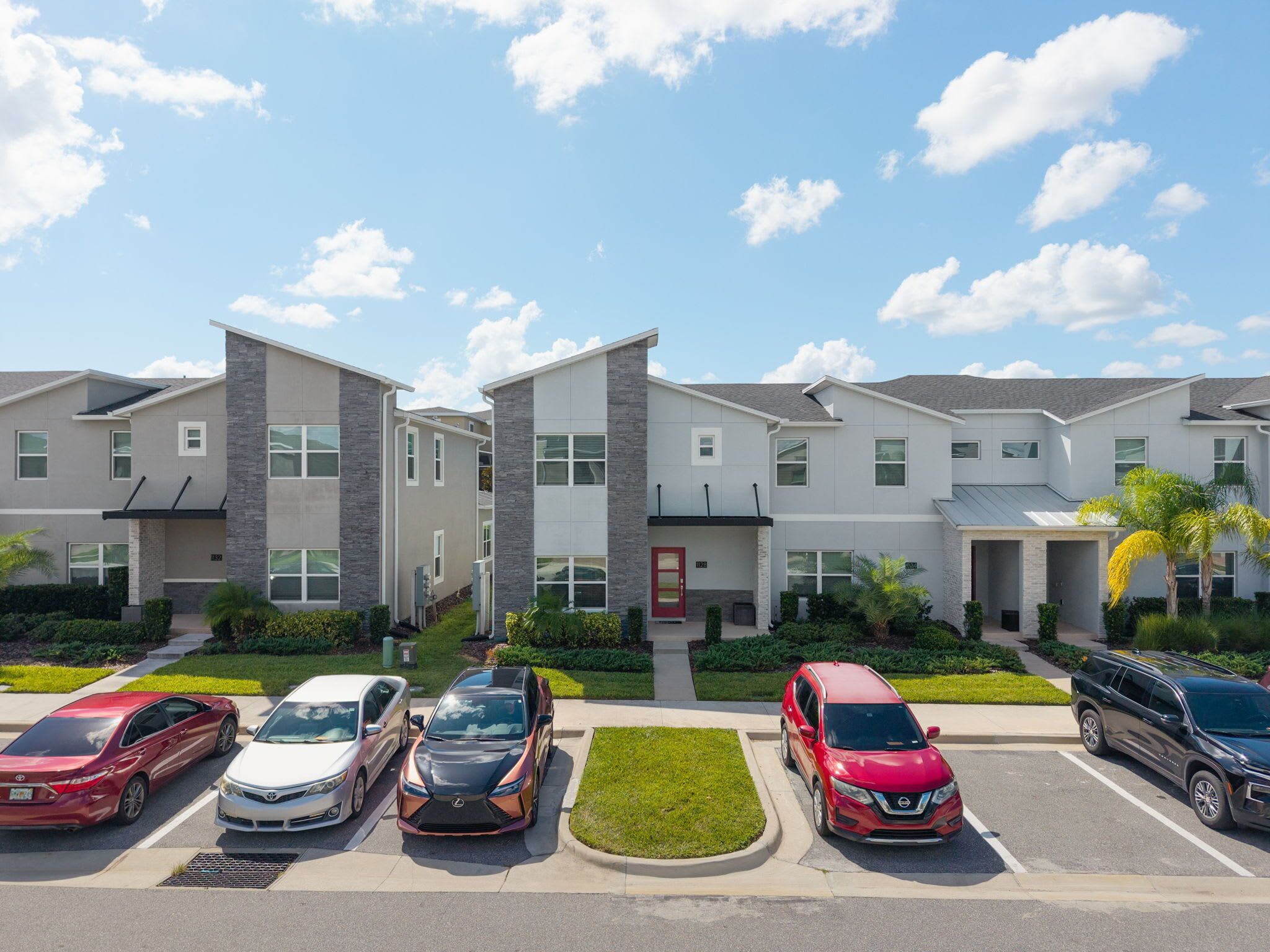 Un immeuble d’appartements moderne, doté de nombreuses unités, d’un parking et surplombant un ciel bleu dégagé.