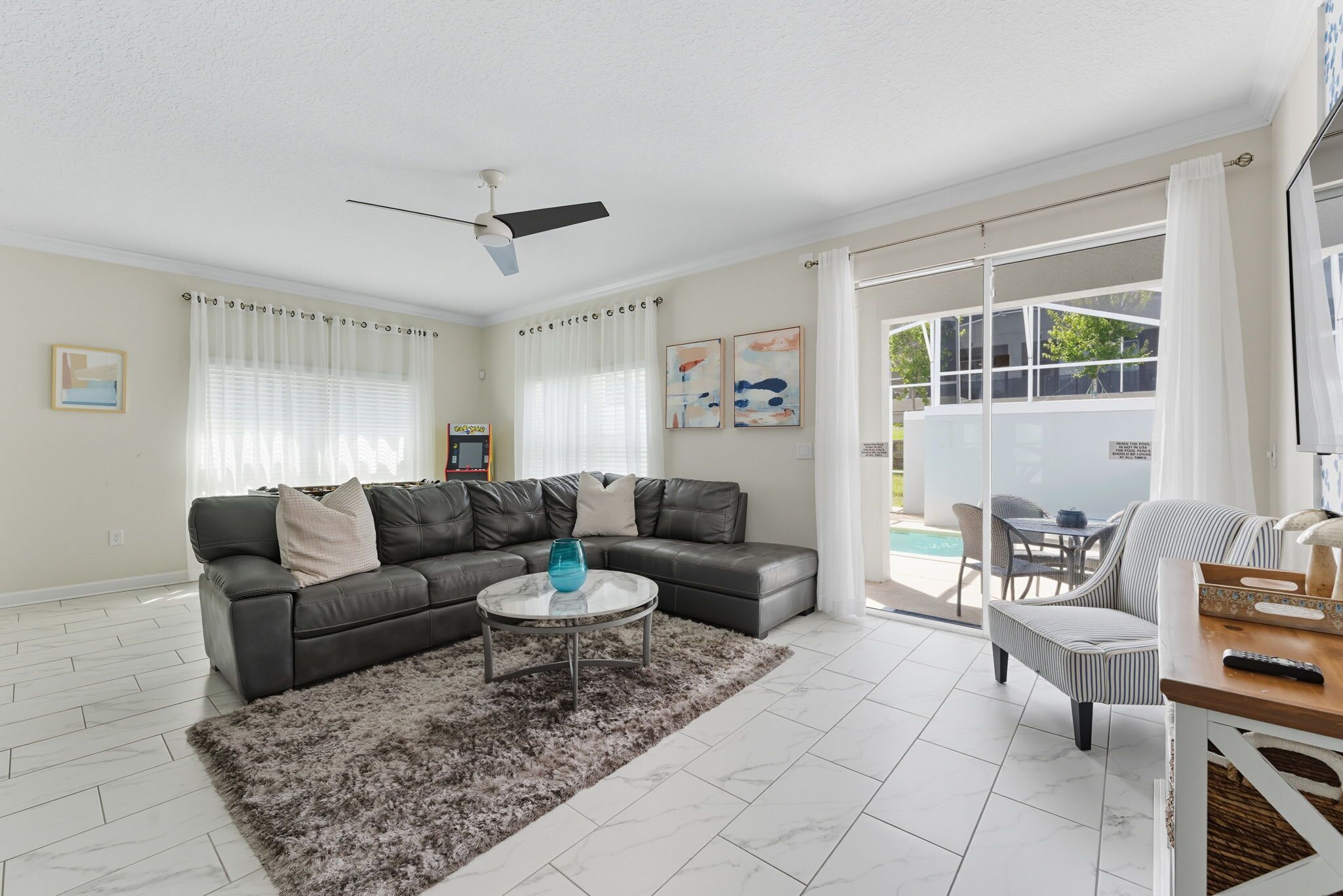 A modern living room with a sectional sofa, a round coffee table, and a ceiling fan.
