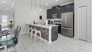 Cozinha moderna com ilha central, eletrodomésticos de aço inoxidável e iluminação pendente.