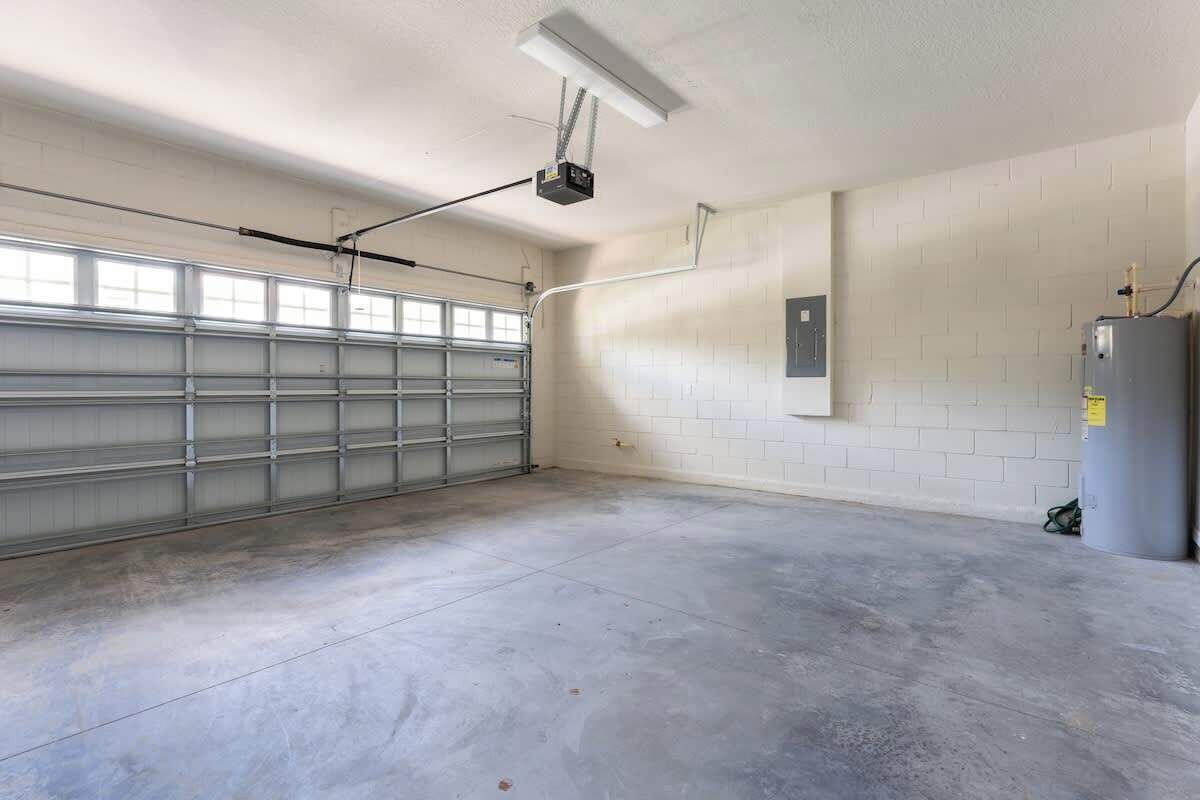 A spacious garage with a concrete floor, a garage door, and a water heater on the right.