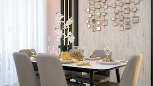 A dining area with a table set for four, a decorative wall with mirrors, and a plant with white flowers. - Magical Stay, Mickey and Harry Potter Rooms (Kissimmee)
