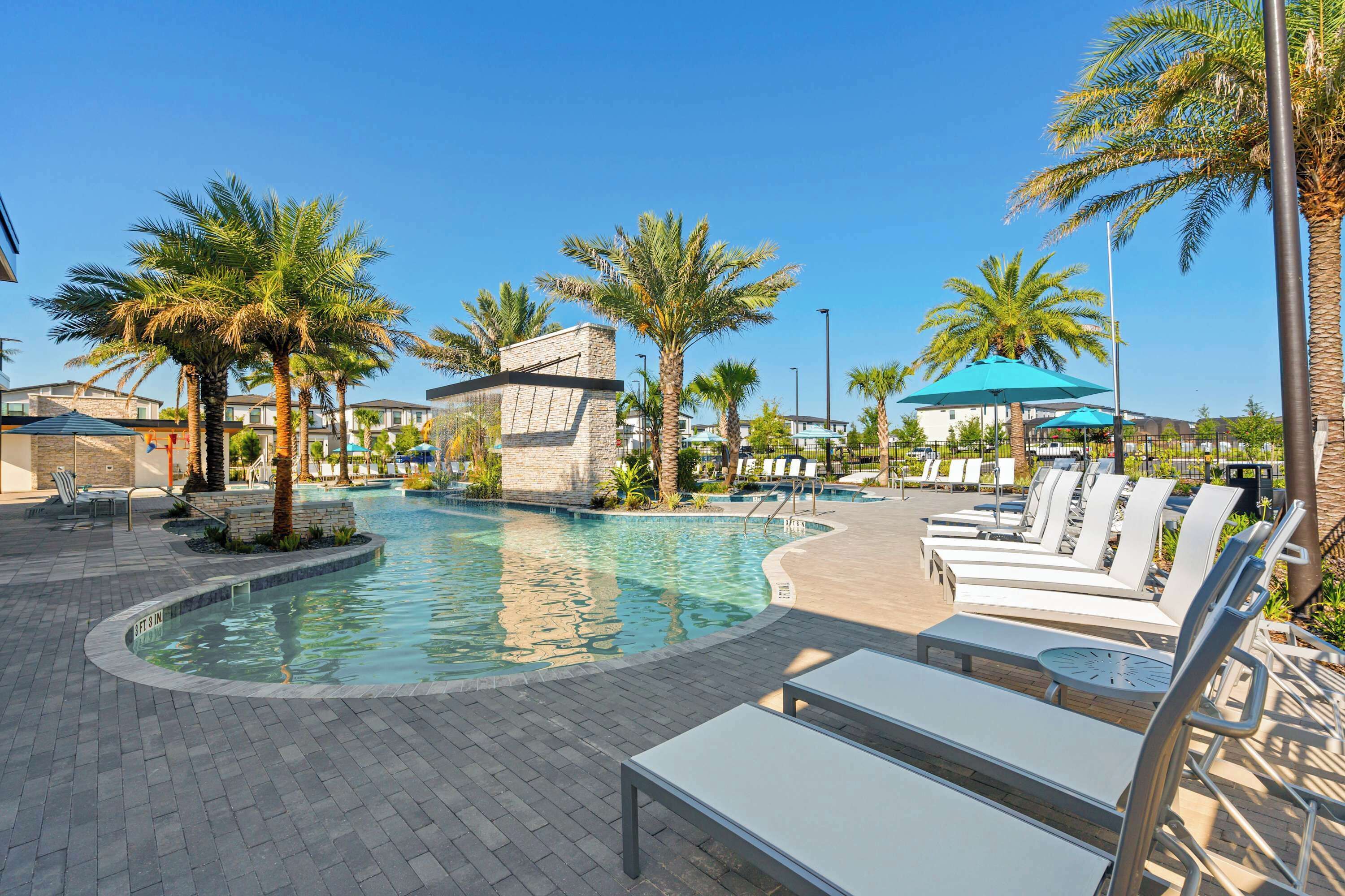A pool area with lounge chairs and palm trees.