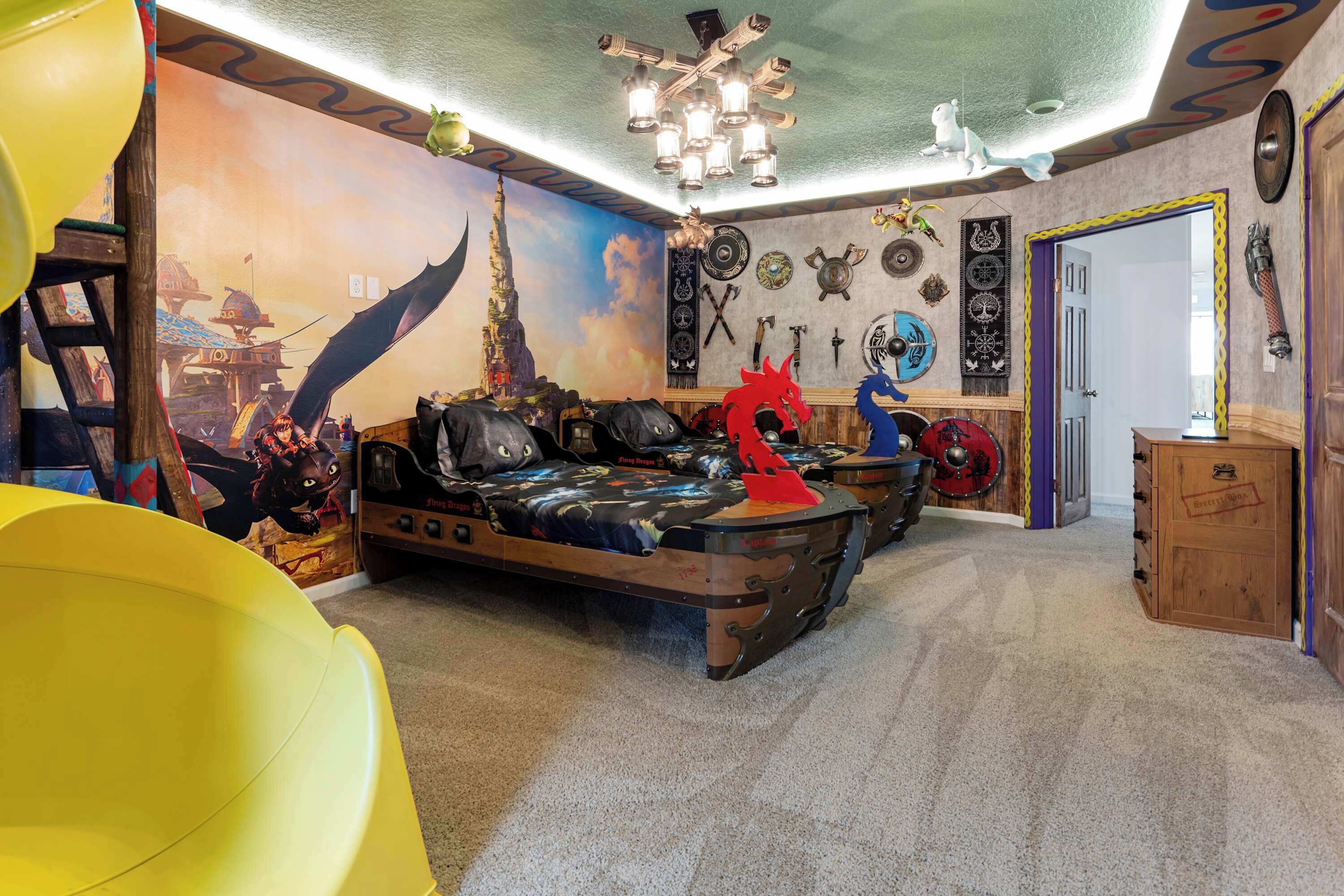 Una habitación con una cama, un sillón amarillo y una pared decorada con varios objetos, incluyendo un dragón, espadas y un mural.