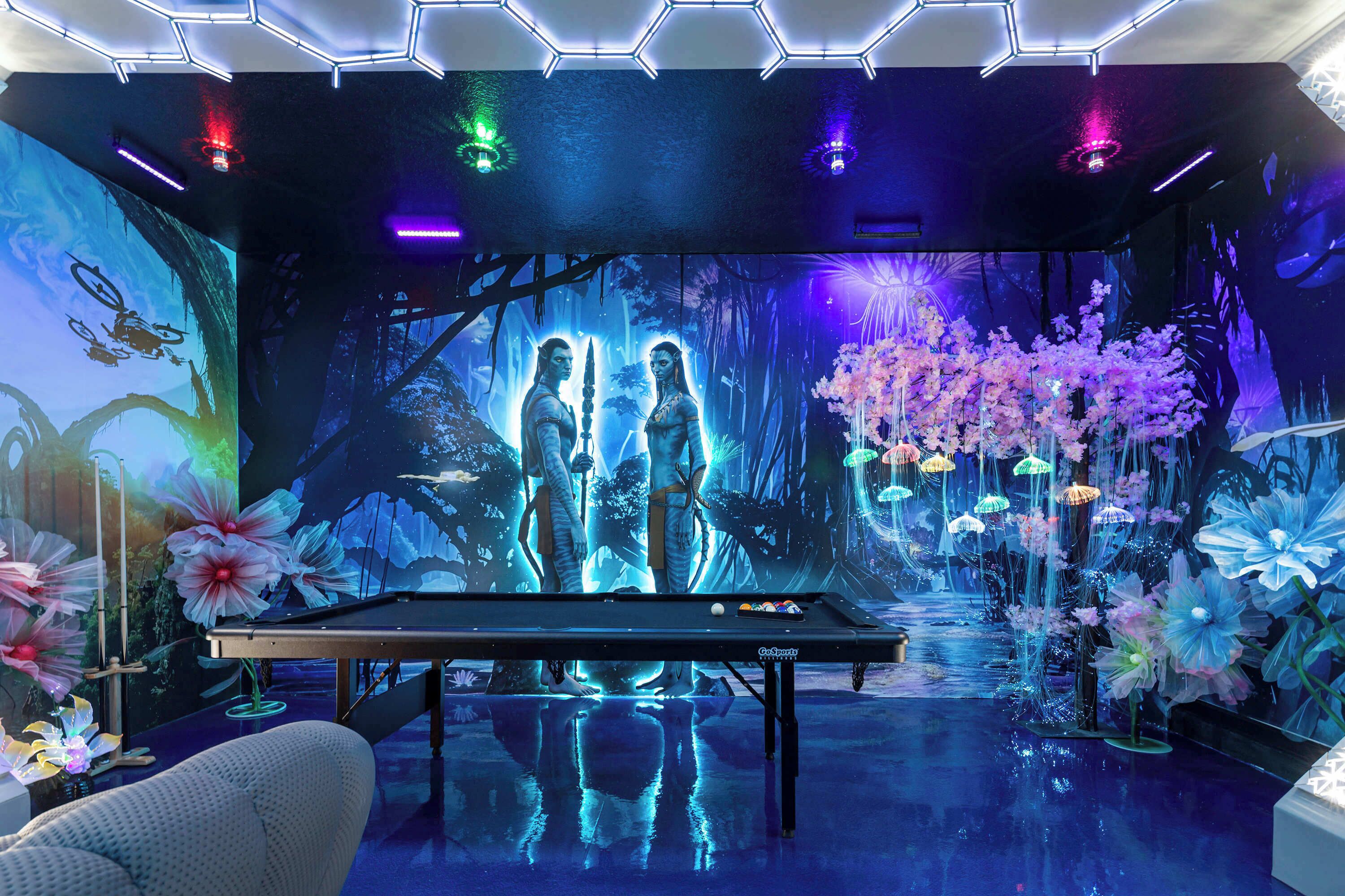 A pool table in a room with a digital forest mural, a pool table, and decorative flowers.