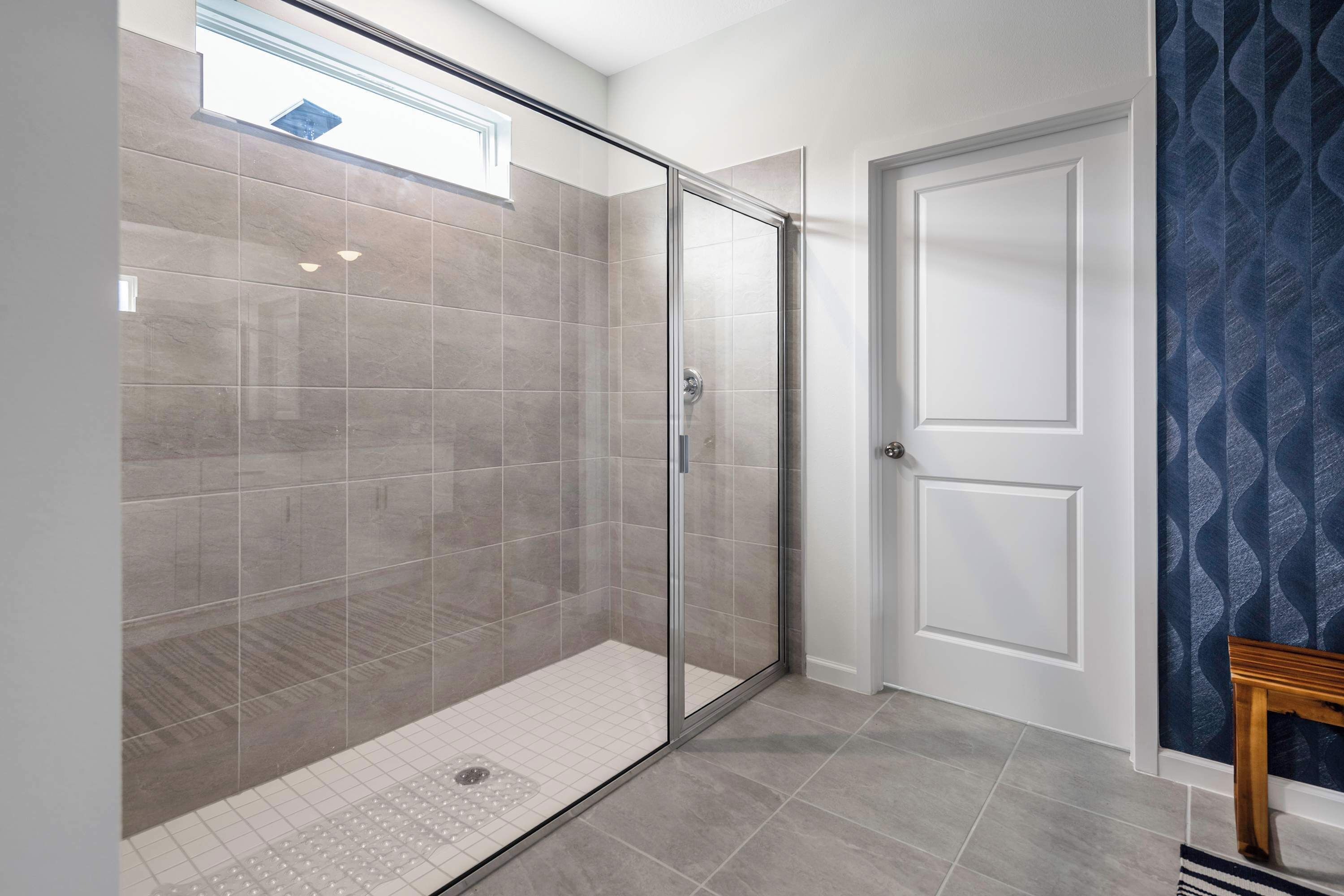 A modern bathroom with a glass shower enclosure, tiled walls, and a door with a decorative panel.