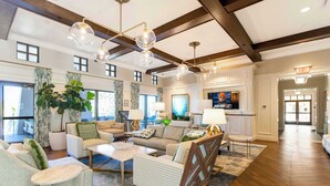 A spacious living area with a high ceiling, wooden beams, and a large window. There are multiple seating options including a sofa, armchairs, and a coffee table. - Luxury 9BR Solara Home, Themed Fun & Pool (Kissimmee)