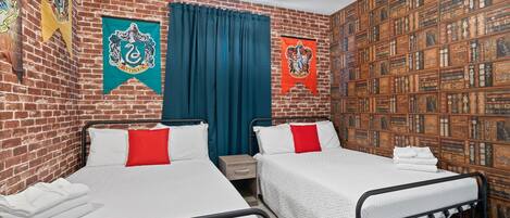 A room with two beds, a brick wall, and a bookshelf.