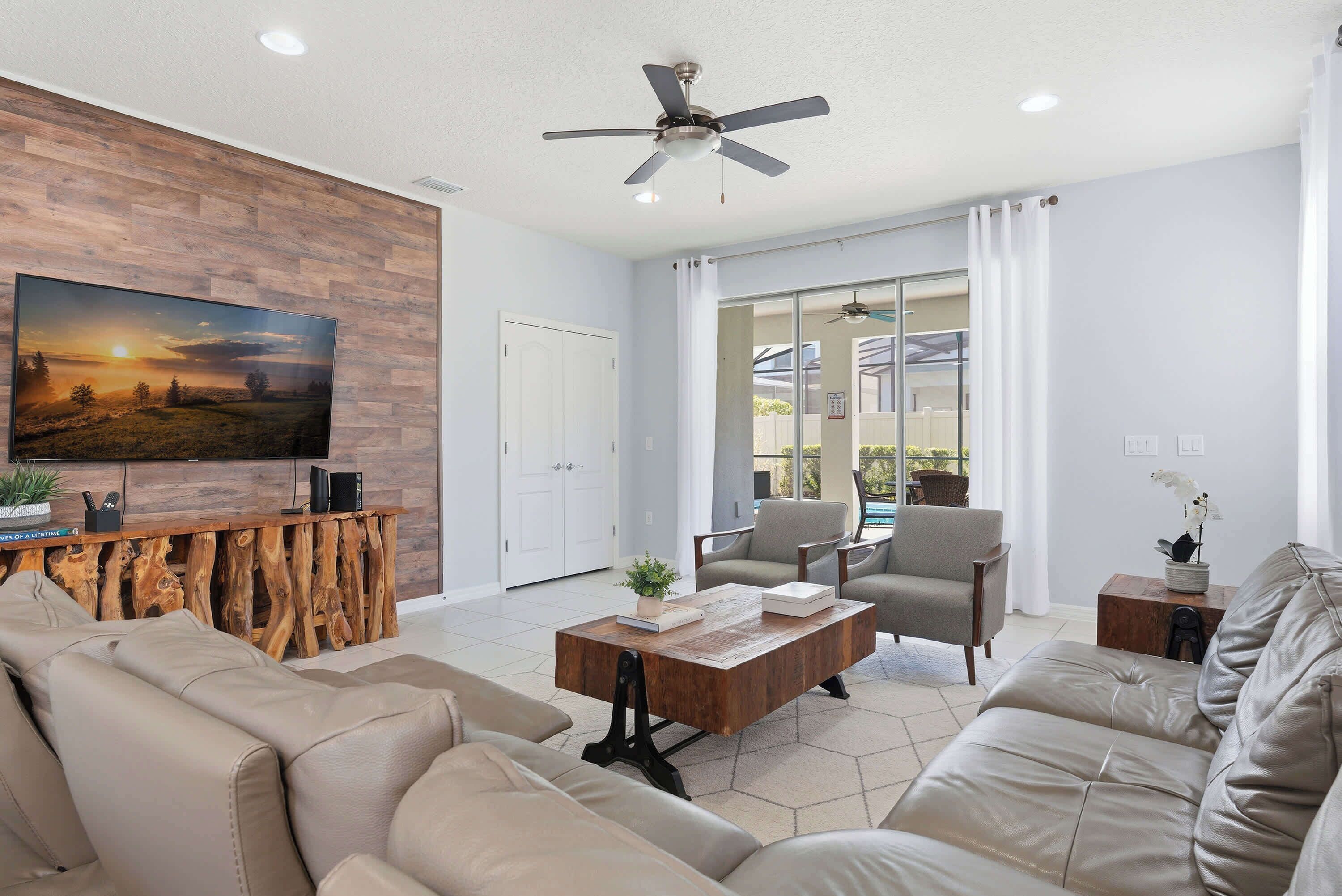 A living room with a sofa, coffee table, TV, and ceiling fan.