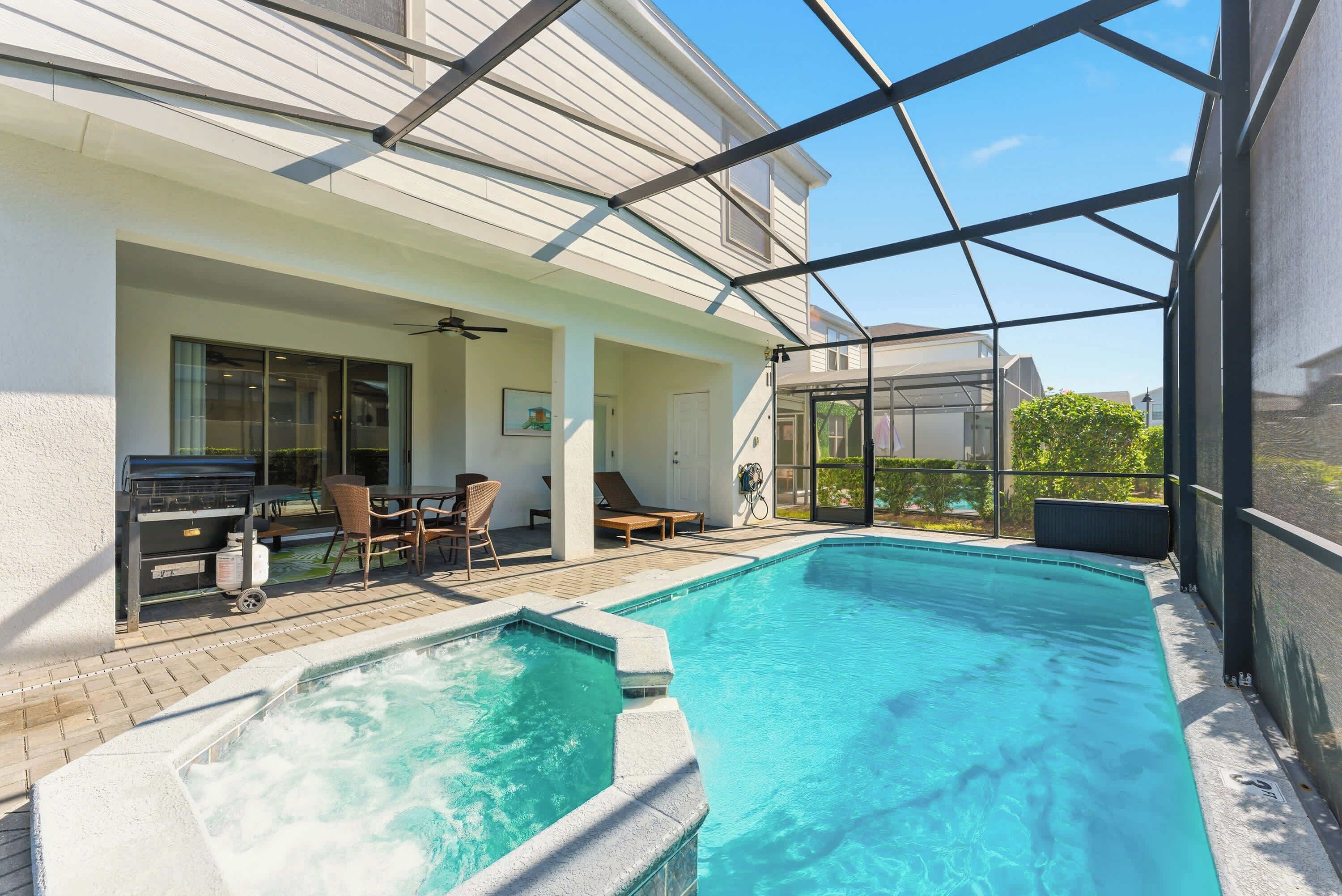 A swimming pool with a hot tub, outdoor seating, and a covered patio area.