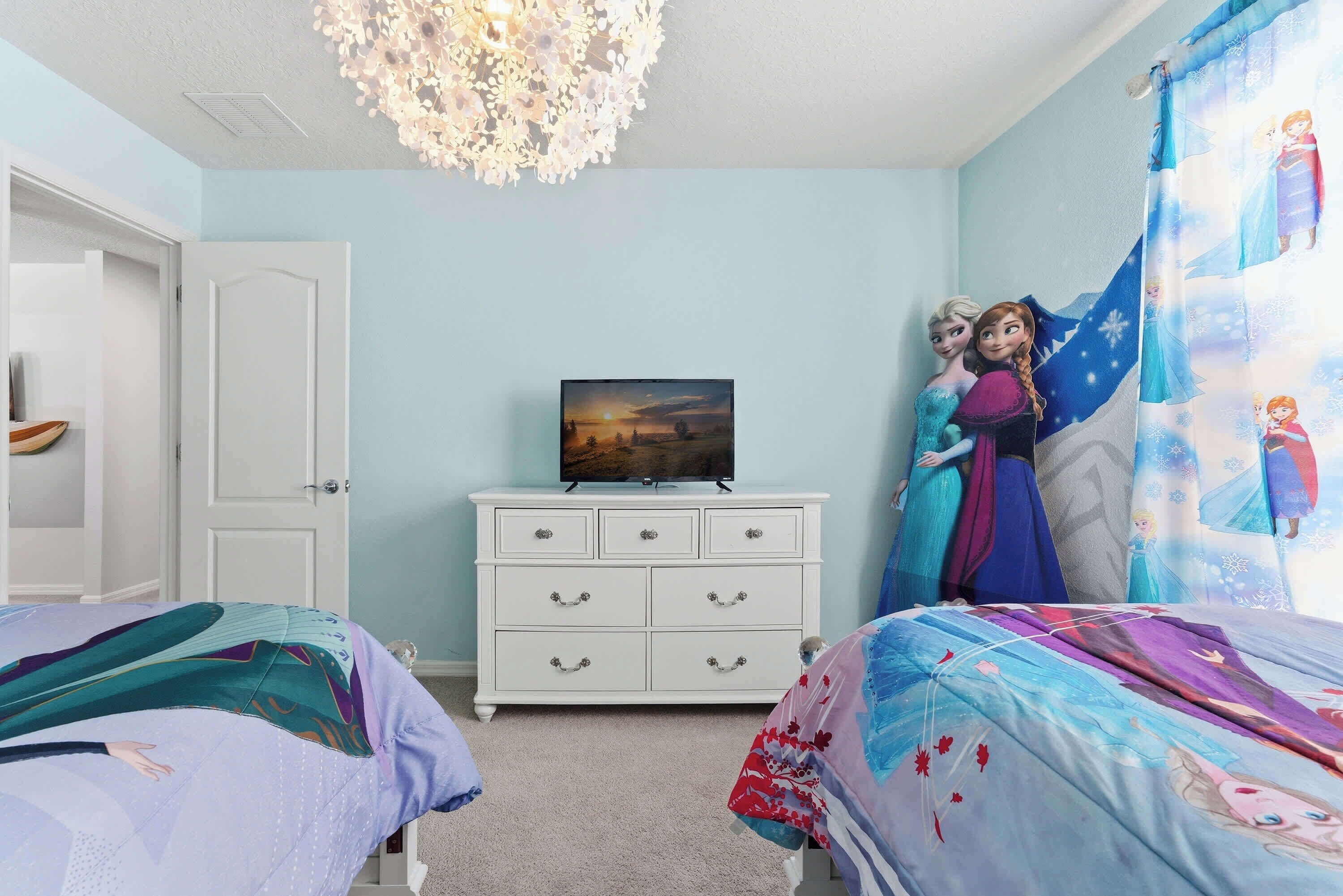 A bedroom with two beds, a dresser, a television, and a decorative ceiling light.