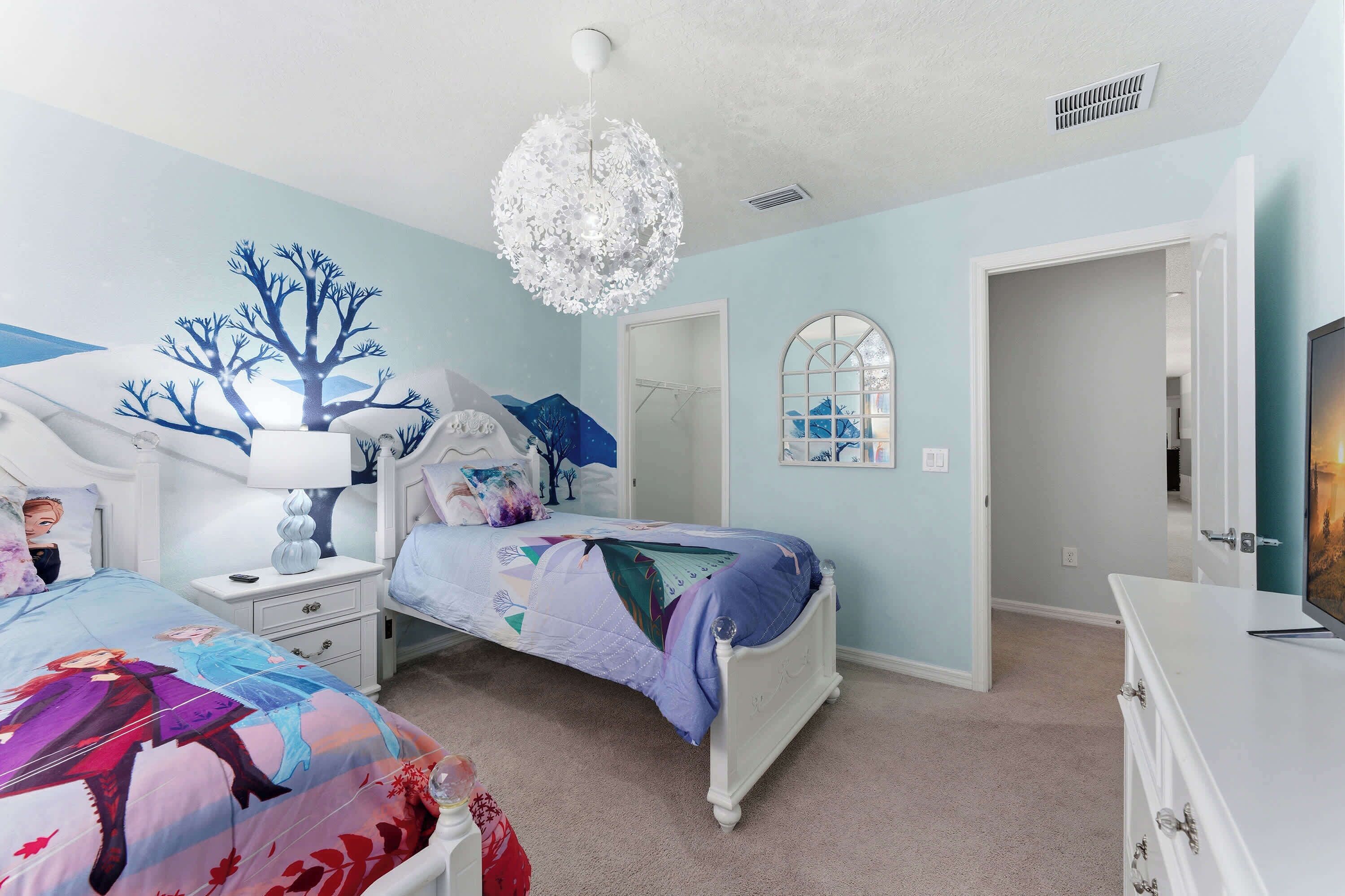 A bedroom with a bed, nightstands, a dresser, a chandelier, a mirror, and a door.