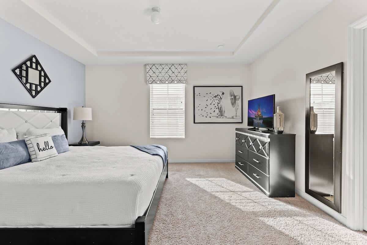 Une chambre à coucher avec un lit, une commode et des œuvres d’art accrochées aux murs.