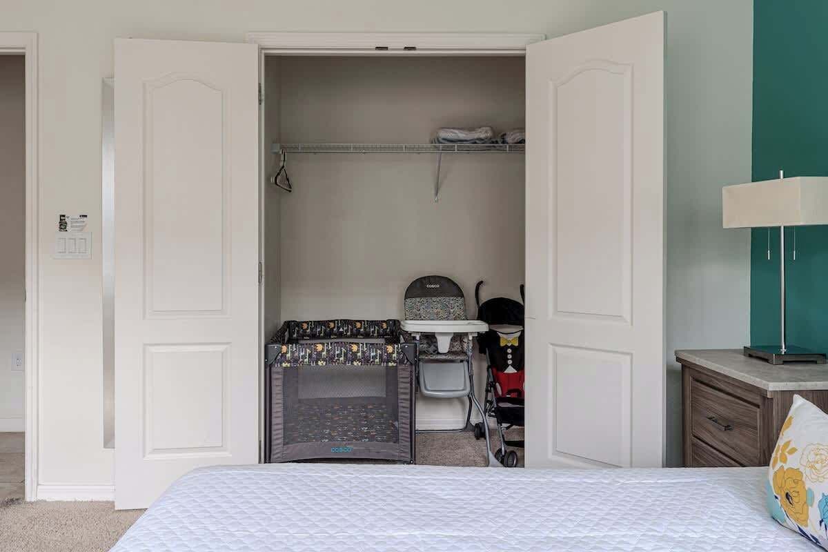 A bedroom with a bed, a crib, a changing table, and a wardrobe.
