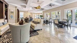 A spacious living area with a sofa, a dining table with chairs, and a ceiling fan. - Private Pool at Solterra 4BR Townhome (Davenport)
