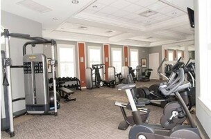 A gym with cardio machines, weightlifting equipment, and dumbbells.