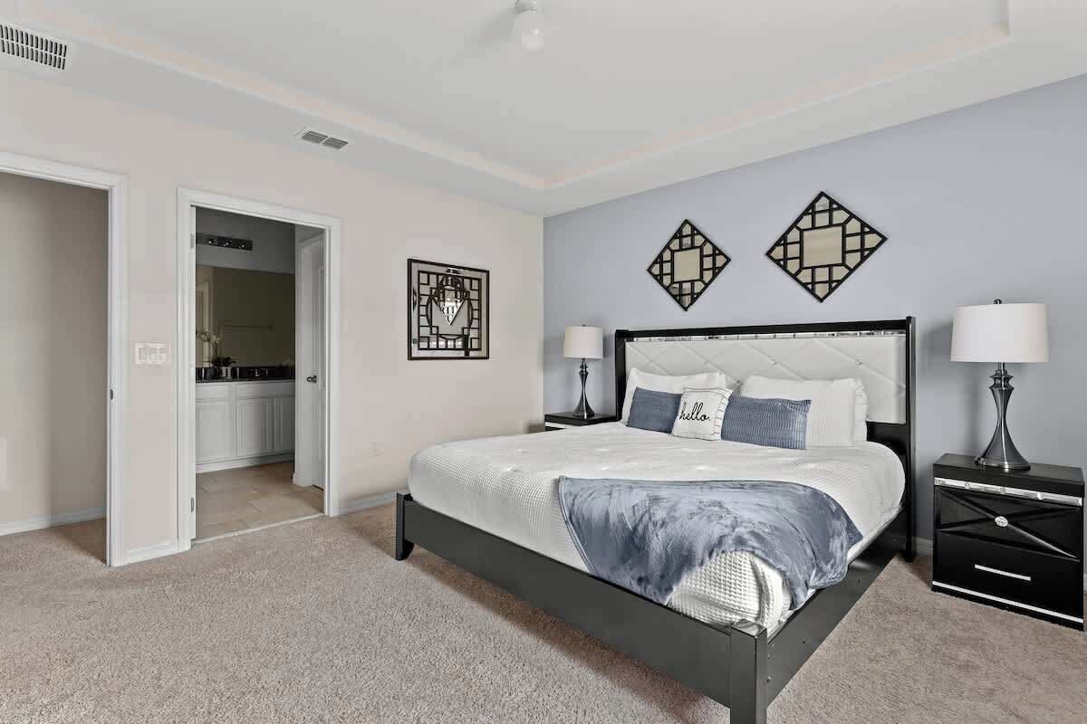 Een slaapkamer met een bed, nachtkastjes en een deur naar een badkamer.