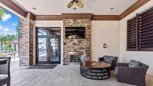 An outdoor patio with a stone fireplace, wicker furniture, and a ceiling fan. - Private Pool at Solterra 4BR Townhome (Davenport)
