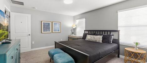 Un dormitorio con cama, banca, cómoda y mesita de noche.