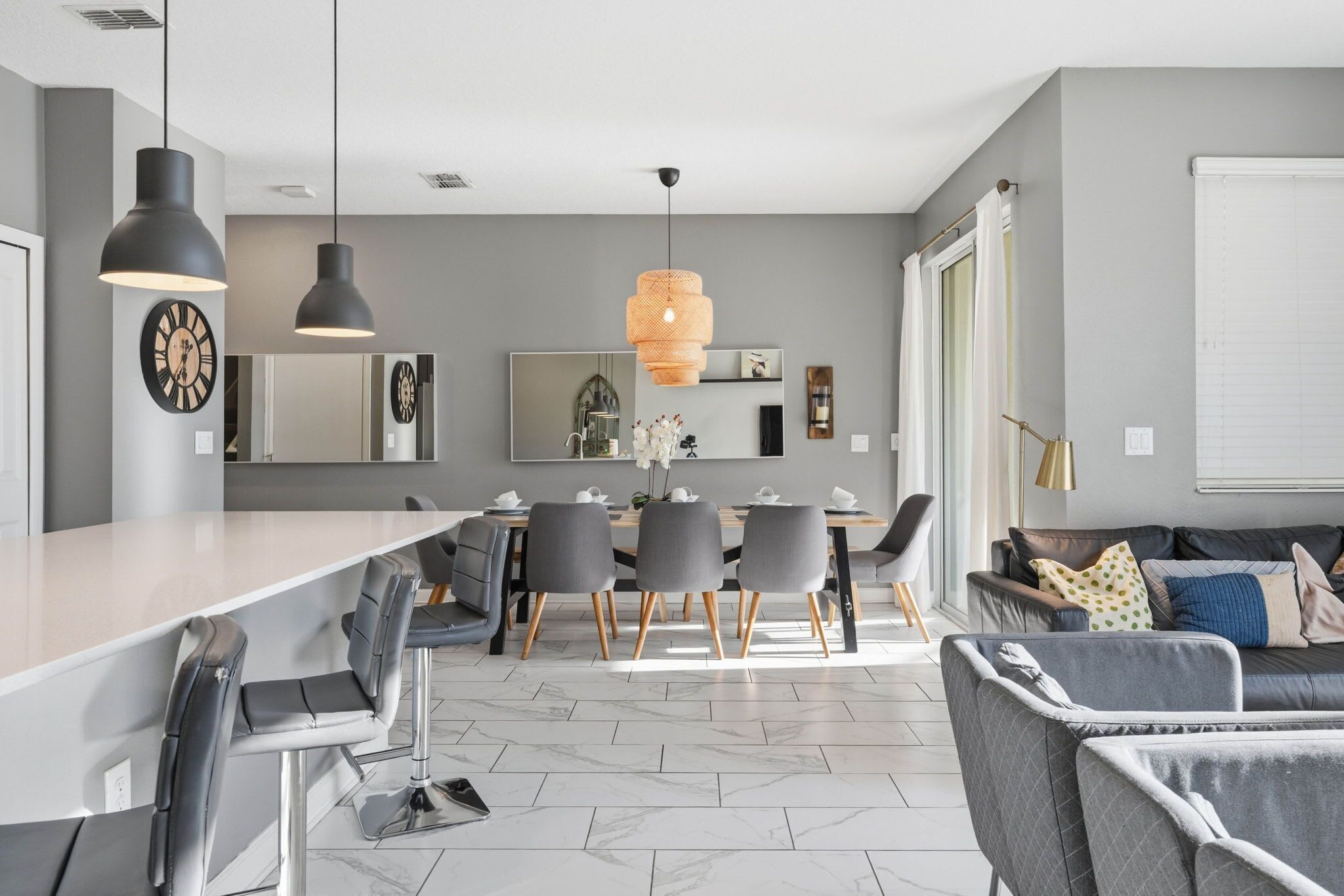 Cocina moderna con comedor, que incluye una isla grande, sillas grises e iluminación colgante.
