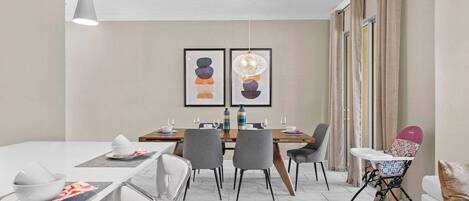 A modern dining area with a table set for four, chairs, a high chair, and a sofa.